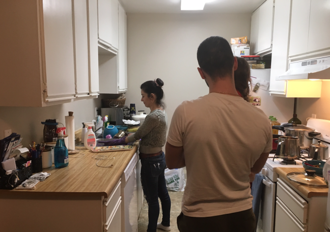 Lilia Tarverdi, left, cooks at home in Tujunga while her brother Argisht, right, holds one of her young children. Argisht, his older brother and their parents recently arrived as refugees from Iran after waiting nearly three years in Vienna.