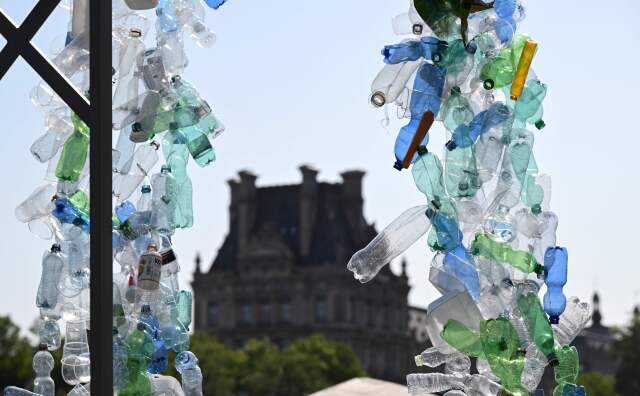 An array of clear, blue and green plastic bottles frame an old building in the background