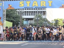 a bunch of runners race away from the starting line of a race