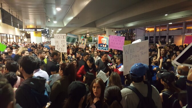 Protesters hold signs outside Terminal 2 at Los Angeles International Airport on Sunday, Jan. 29, 2017, amid calls to release immigrants detained under President Donald Trump's executive order effectively banning travel from seven majority Muslim nations.