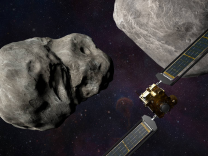 A computer generated image of a spacecraft with two large wing-like extensions headed toward a pair of asteroids floating in space.