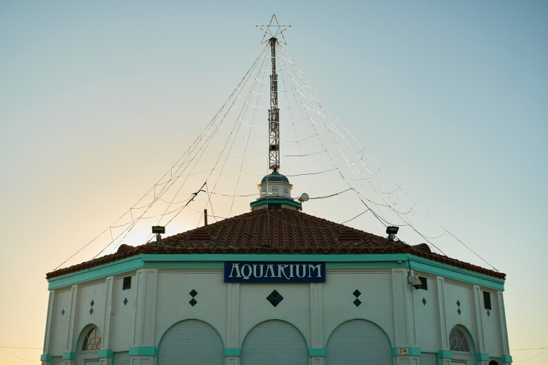 A hexagonal building is center frame with a blue and white sign that reads "Aquarium" on the front.