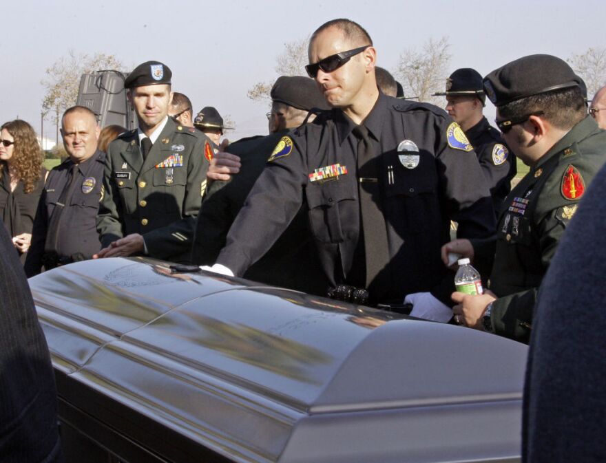 A Riverside police officer touches the casket of Officer Ryan Bonaminio at an outdoor memorial service at the Riverside National Cemetery in Riverside, Calif., Tuesday, Nov. 16, 2010.  Bonaminio was shot and killed Nov. 7 after he pulled over the driver of a stolen big-rig cab and was led down a dark path into a park.