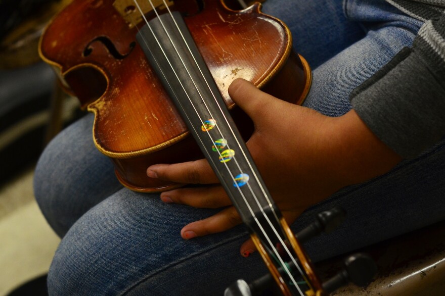 Some of the students' violins have stickers to mark finger positions to help them remember the notes.