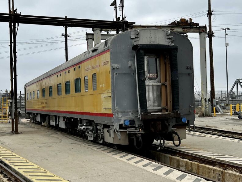 A train car with yellow exterior at a station.