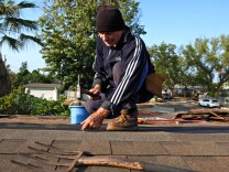 File: Roofer Michal Swiderski works on putting in a new roof of his home in the Panorama City section of Los Angeles on Saturday, Oct. 17, 2015. 