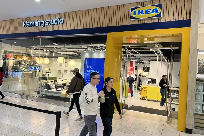 Shoppers walk by an IKEA storefront that has yellow, blue and wood colors near the front. 