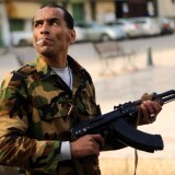 A Libyan rebel searchs for snipers as they protect a march gathering thousands of people in the streets of Benghazi on March 23, 2011 to show their support for an internationally-enforced no-fly zone over Libya. 