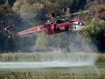 Fire officials said Monday that 12 helicopters and 967 firefighters are battling the 3,800 acre Hathaway Fire in Riverside County in heavy chaparral and timber. 
(File photo: Helicopters pick up water from Lake Hughes to put out flames at the Powerhouse Fire in northwest L.A. County in May).