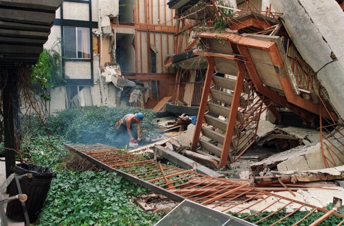 A construction worker using a chain on January 24, 1994, starts to cut up some of the destroyed walls in the courtyard of Northridge Meadow, the apartment complex that collapsed during the Northridge earthquake. Sixteen people were killed when the building collapsed during the quake. Councilman Tom LaBonge is now proposing an inventory of so-called "soft-story" buildings — those where the top stories could collapse onto the lower floor during a major temblor.