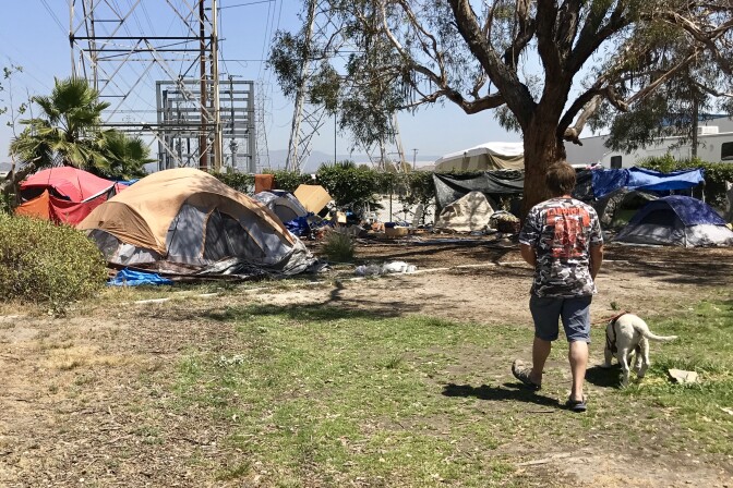 A homeless man walks back to his tent along the Santa Ana River. Advocates for the homeless want to install port-a-potties on nearby land owned by the city of Anaheim.