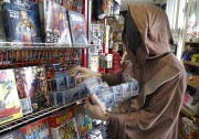 File: Kip Henniquan, who is in costume as a Jawa character from "Star Wars", restocks a shelf at the New Dimensions Comics store in Cranberry, Pa., Butler County, as part of Free Comic Book Day on Saturday, May 5, 2012.