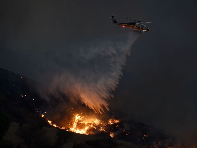 TOPSHOT - A firefighting helicopter makes a drop at Fair Oaks Canyon as they battle a blaze dubbed the "Sand Fire" in Santa Clarita, California on July 24, 2016.  
A fire burning out of control in Southern California has grown to a massive 20,000 acres, officials said on July 24, as residents in an area north of Los Angeles were forced to evacuate. / AFP / Mark Ralston        (Photo credit should read MARK RALSTON/AFP/Getty Images)