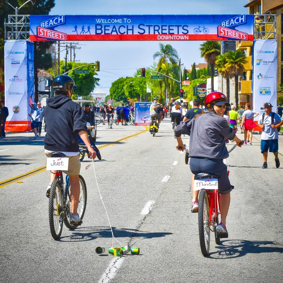 Newly married bicyclists pedal through Long Beach during a Beach Streets event.