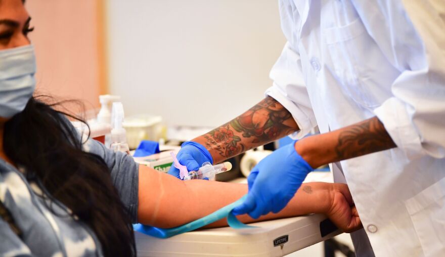 A phlebotomist draws blood during a no-cost COVID-19 antibody testing.