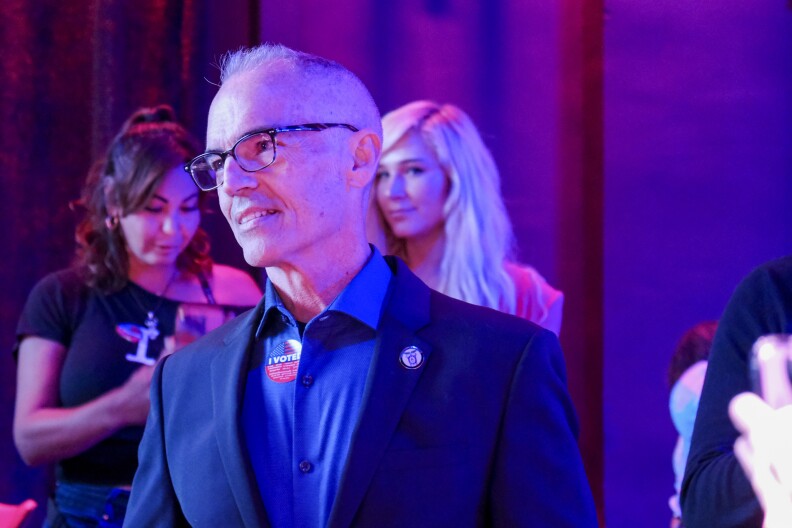 A view of Mitch O'Farrell, a man with a light skin tone, from the chest up while he's in a room with a blue hue. He's looking off to the side.