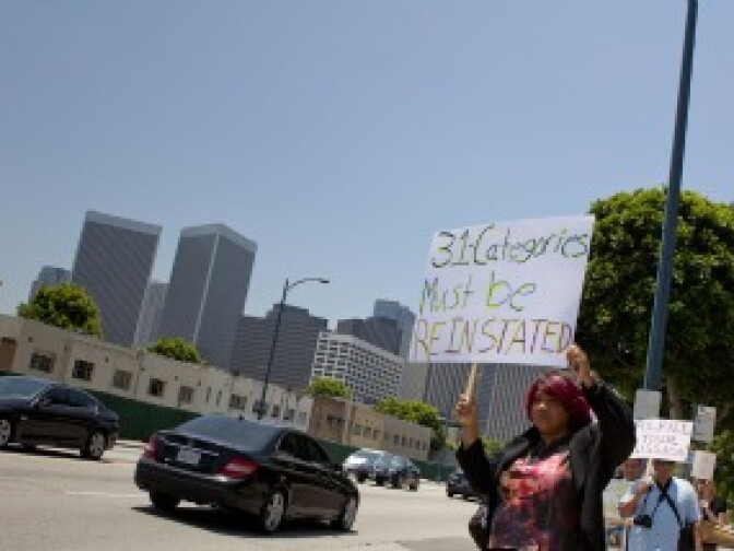 Pepper Mashay, a dance and blues artist, held a sign for passing motorists near the Beverly Hilton where musicians protested the cancellation of more than 30 categories in this year's Grammy Awards. (May 26, 2011)