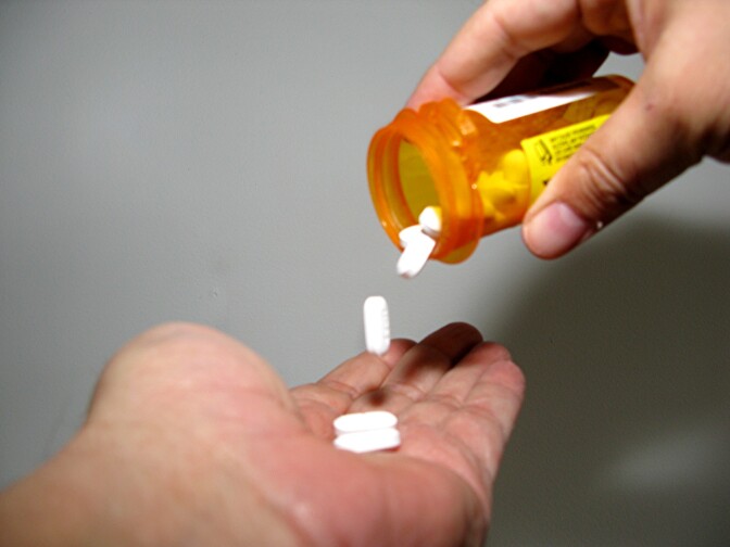 A person pours prescription pills into their hand