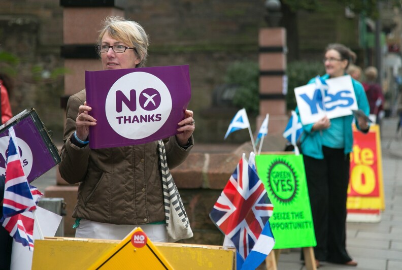 EDINBURGH, SCOTLAND - SEPTEMBER 18:  Yes and No supporters react to motorists passing the Church Hill Theatre polling place in Morningside on September 18, 2014 in Edinburgh, Scotland. After many months of campaigning the people of Scotland today head to the polls to decide the fate of their country.  The referendum is too close to call but a 'Yes' vote would see the break-up of the United Kingdom and Scotland would stand as an independent country for the first time since the formation of the Union.  (Photo by Matt Cardy/Getty Images)