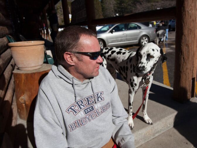 Rick Heltebrake relates the tale of how Christopher Dorner hijacked his truck on Highway 38 to reporters while his dog Suni hangs around.