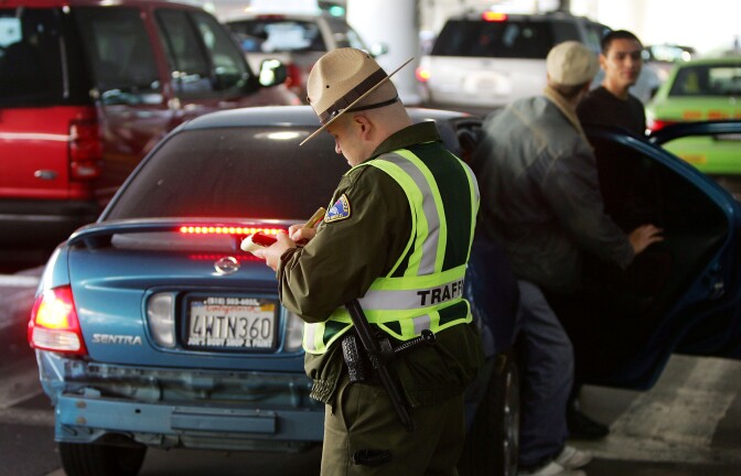  A parking enforcement officer gives a citation to a driver who stopped in the wrong place to pick up arriving travelers at Los Angeles International Airport (LAX) on November 23, 2004 in Los Angeles, California. 