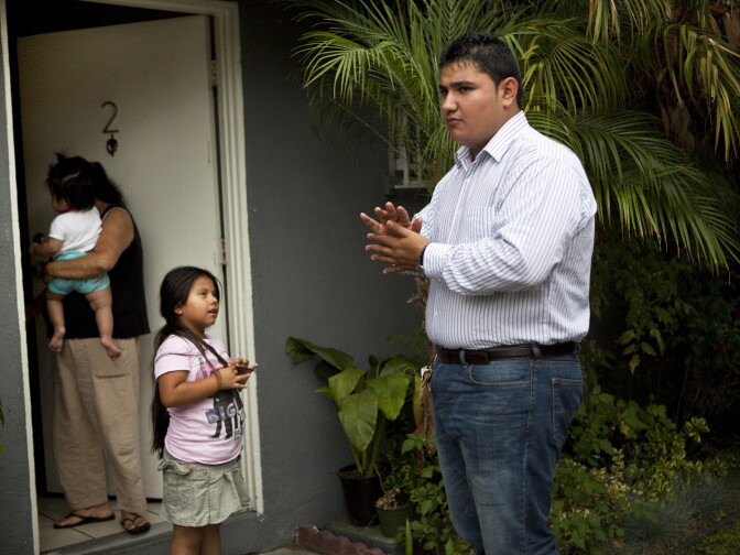 Los Angeles, CA: July 12, 2012 - Ronald Aldana stands near the front door of his home, his girlfriends mother, Julia, and family friends hang out, watching Ronald cook on the grill in the front yard.