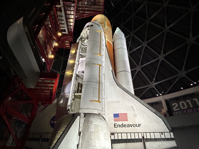 A space shuttle stands in it's launch position. A hatch on the shuttle is open. 