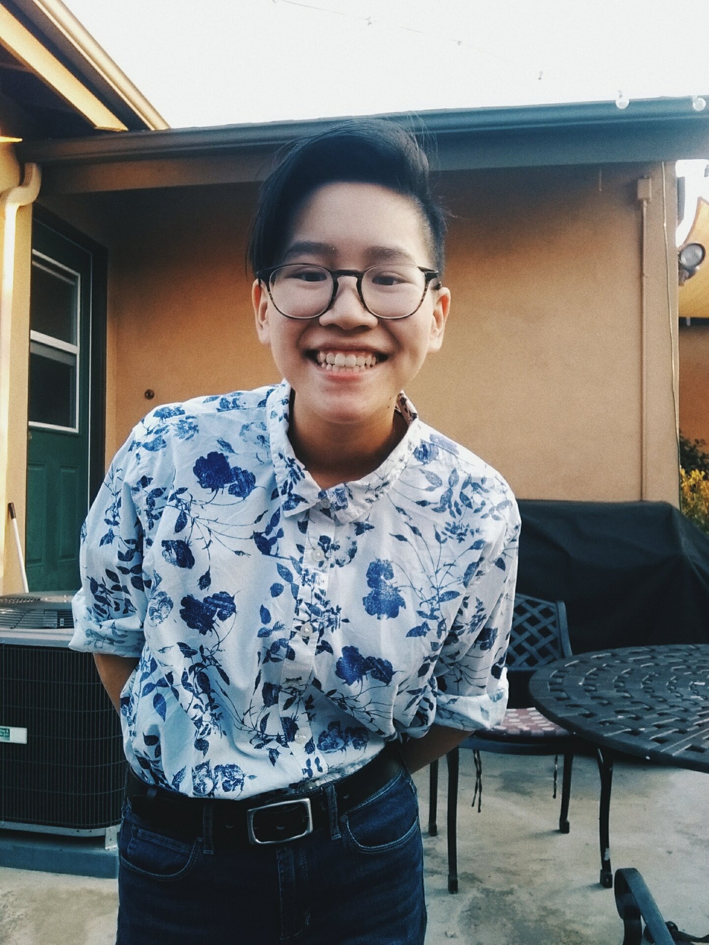 Victoria Lum smiles for the camera in glasses and a flowery collared shirt.
