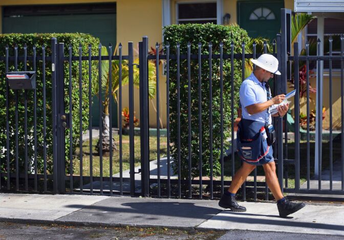 A mailman for the U.S. Postal Service delivers mail in Miami, Florida. The U.S. Postal Service recently reported a record annual yearly loss of $15.9 billion. The USPS plans to stop delivering mail on Saturdays but continue to deliver packages six days a week under a plan intended at saving about $2 billion annually, 