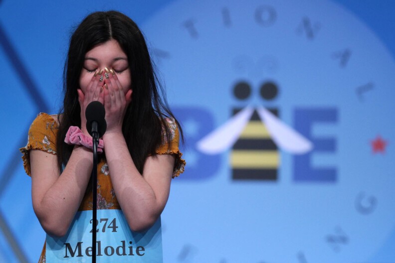 A girl covers her mouth as she stands at the mic at the Annual National Scripps Spelling Bee