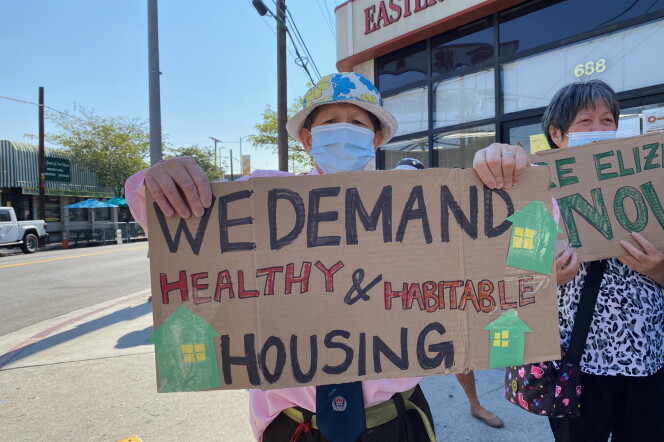 a man wearing a hat and face mask while protesting holds a sign that reads "We demand healthy and habitable housing."