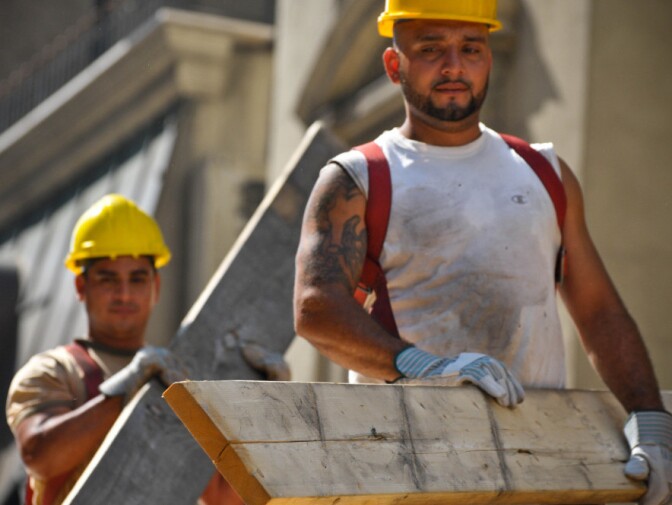 Construction workers lug building materials at a job site in New York's midtown Manhattan. While a number of industries added jobs in December, the construction sector lost 16,000.