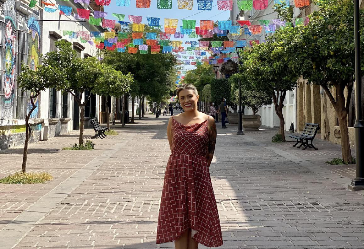 An image of the author, Flor Arellano, on a tree-lined brick street in Tlaquepaque, Mexico.