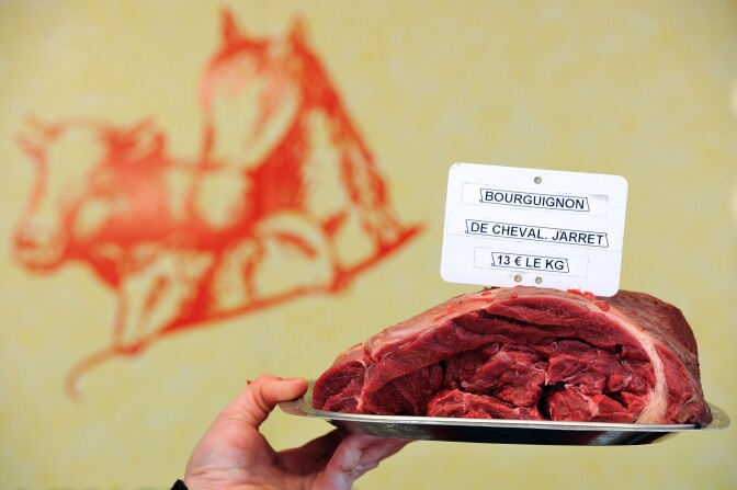 A butcher holds a piece of horse meat at a horse butchery in Anzin, northern France, on February 22, 2013.