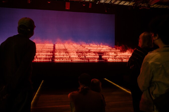 People watch a series of rows of what appears to be fire, but is actually created with light and water.