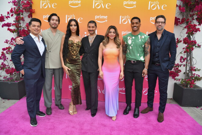 7 people stand side-by-side, a colorful backdrop is behind them with logos for Amazon Prime Video and the show "With Love."