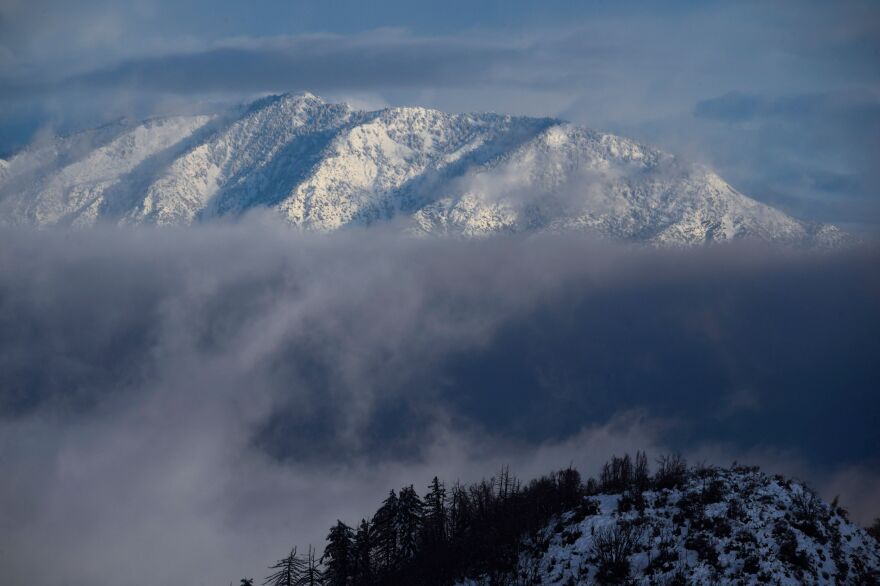 Snow capped mountains are visible above a bank of clouds.