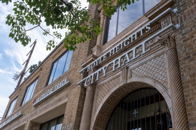 A brick building with ornate columns and an arched entryway. Silver letters are attached to the building spelling out, "Boyle Heights City Hall."