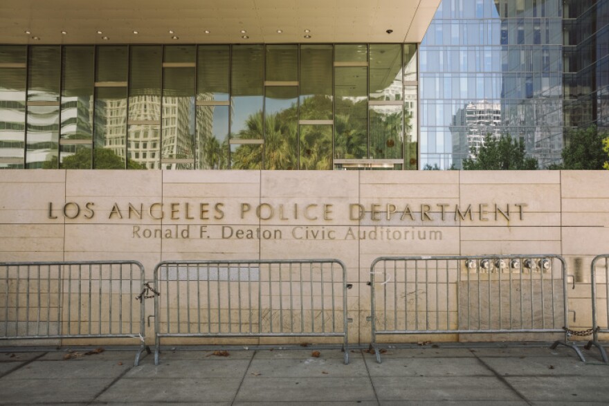 A light brown wall with the words Los Angeles Police Department in block letters embedded in the fascade. It the front of the LAPD headquarters in front of City Hall.