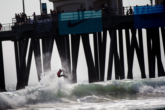 A surfer catches air near the Huntington Beach pier during the U.S. Open of Surfing competition on Friday, August 3, 2012.