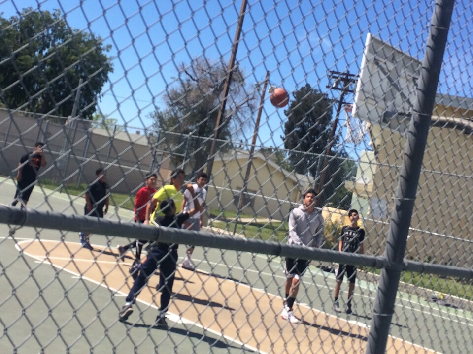 Children and teens play basketball at San Fernando Gardens housing in Pacoima in March, 2016. Just four months earlier, a 15-year-old was shot and killed on the block, an incident local police called gang-related.