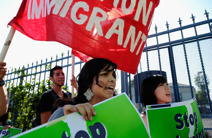 LOS ANGELES, CA - AUGUST 15:  Protesters with Coalition for Humane Immigrant Rights of Los Angeles (CHIRLA) hold signs as they march during an anti Secure Communities program demonstration on August 15, 2011 in Los Angeles, California. The demonstrators were picketing in front of St. Anne's Residential Facility, where Homeland Security advisory council's Task Force on Secure Communities was holding a hearing. The program, which was created in 2008, calls for police to submit suspects' fingerprints to US Immigrations and Customs Enforcement so they can be cross-checked with federal deportation order.  (Photo by Kevork Djansezian/Getty Images)