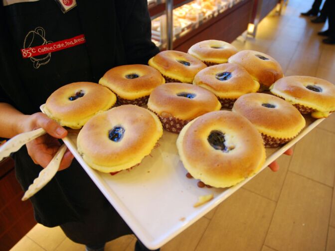 WEST COVINA, Calif. -- A storefront employee restocks one of dozens of display cases with fresh bread at the new 85°C Bakery Cafe on Jan. 16. This company-owned West Covina location is the third to open in the United States, with more openings planned throughout Southern California. The Taiwan-based chain, while new to the U.S. market, operates more than 700 stores worldwide.
