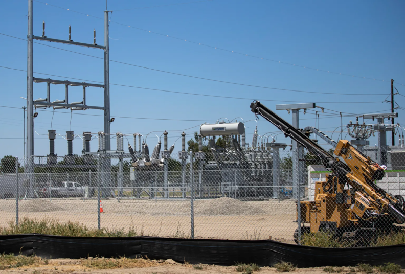 Construction equipment sits in front of an electrical substation.