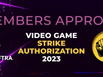 A SAG-AFTRA graphic that includes a hand holding a video game controller reads: "Members approve video game strike authorization 2023." 