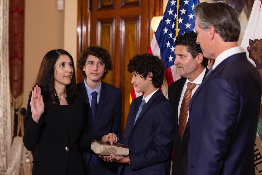 Patricia Guerrero raises her right hand, with her left on a bible held by her son. An American flag is behind her family. Also pictured are another son, her husband and Gov. Gavin Newsom.