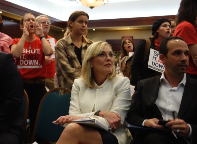                                Los Angeles County Supervisor Kathryn Barger and City Councilman Mitchell Englander remain seated while at a public meeting around them, opponents shout support for the permanent shutdown of Southern California Gas Company's Aliso Canyon natural gas storage field near Porter Ranch.
