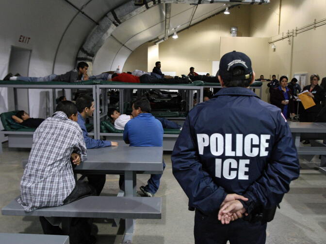 TO GO WITH AFP STORY BY CARLOS MARIO MARQUEZ An Immigration and Customs Enforcement (ICE) officer guards a group of 116 Salvadorean immigrants that wait to be deported,at Willacy Detention facility in Raymondville, Texas on December 18, 2008 early morning. The Willacy facility is used by the US Immigration and Customs Enforcement agency (ICE) to keep illegal immigrants in detention before they are deported. Today, 116 Salvadorean nationals --83 men and 33 women-- were woken up at 4 a.m. and transported in buses under strict surveillance to Harlengen's airport to be taken back to El Salvador.  AFP PHOTO/ Jose CABEZAS (Photo credit should read Jose CABEZAS/AFP/Getty Images)