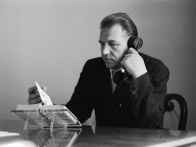A man flips through his desk diary while talking on the telephone on May 18, 1961.