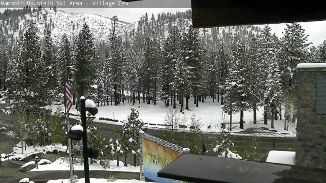 Mammoth Mountain's Village Cam shows snow gathering on trees and rooftops after an unseasonably cold spring storm dropped more than a foot of snow on the resort.